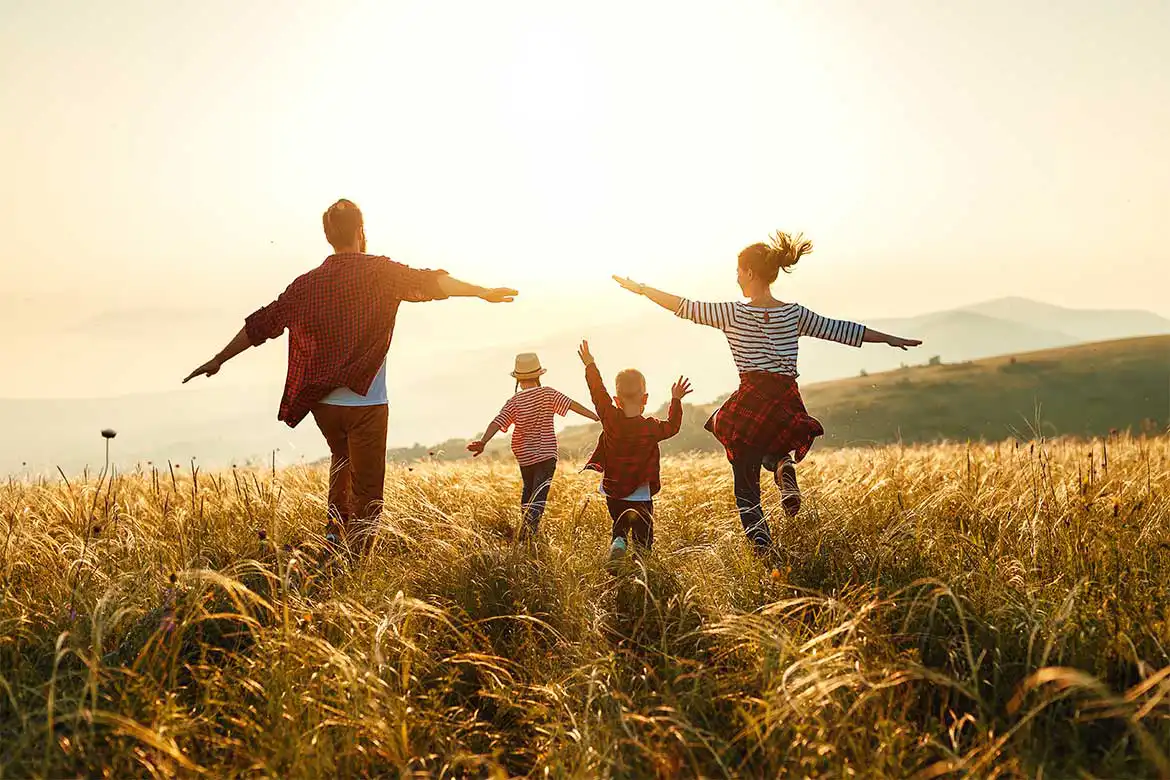 En familie på 4 som springer ute i solskinn en vakker høstdag