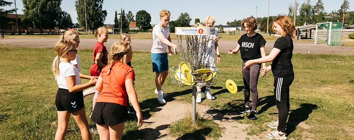 En gjeng barn og ungdom spiller frisbeegolf utendørs