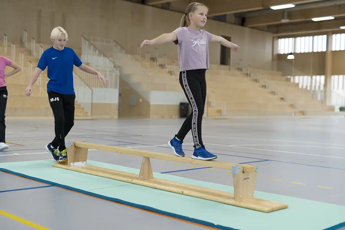 Jente som balanserer på en gymnastikkbenk