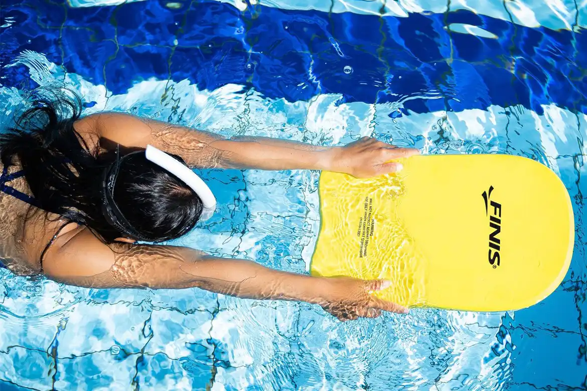 Ung dame som svømmer med kickboard og snorkel