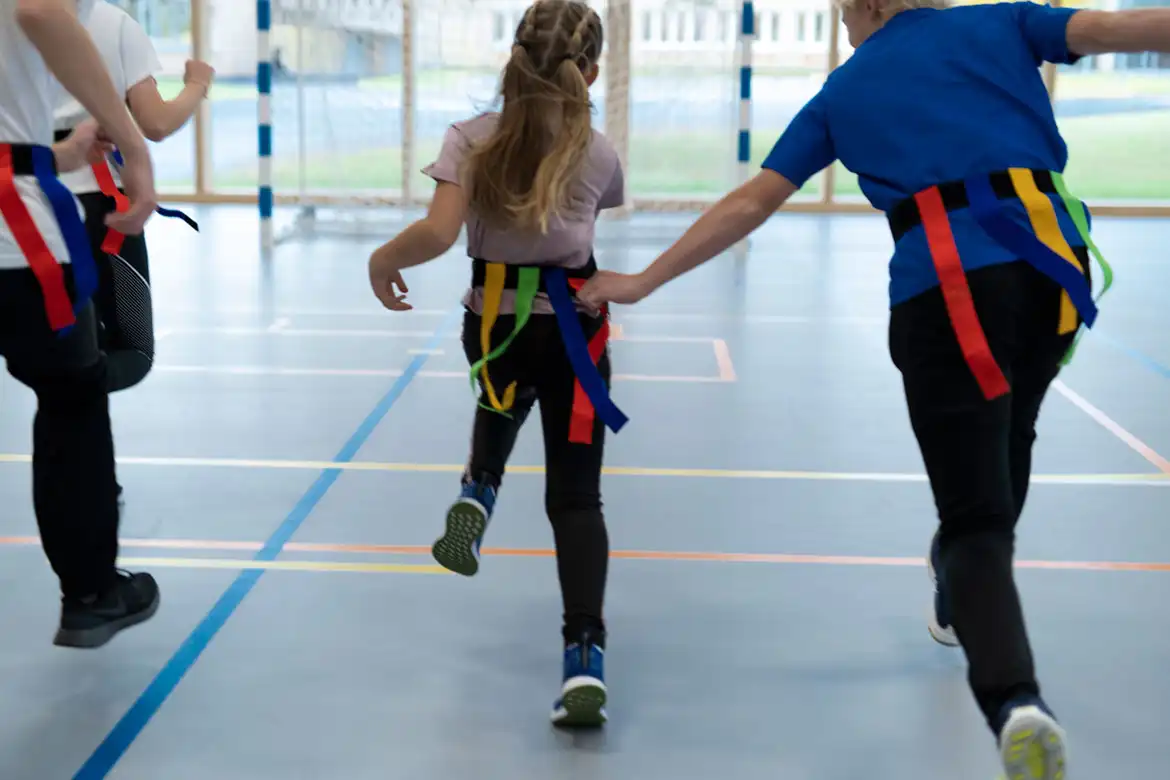 Skoleklasse som leker nappehale lek i gymsalen