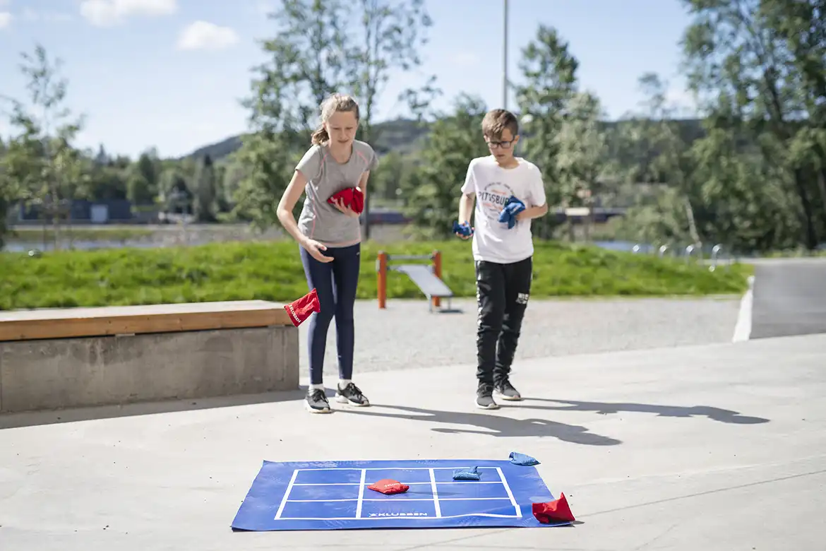 En jente og gutt som spiller tre på rad utendørs i skolegården