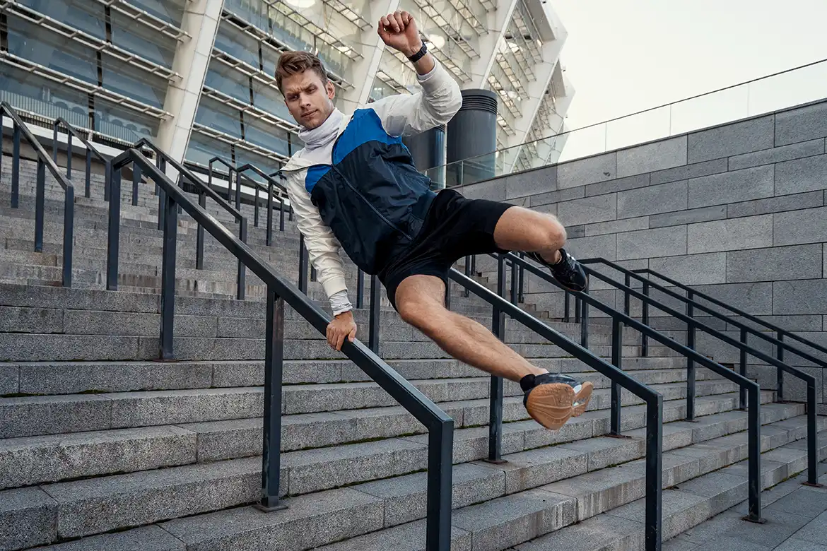 Ung mann som utøver parkour utendørs i en trapp